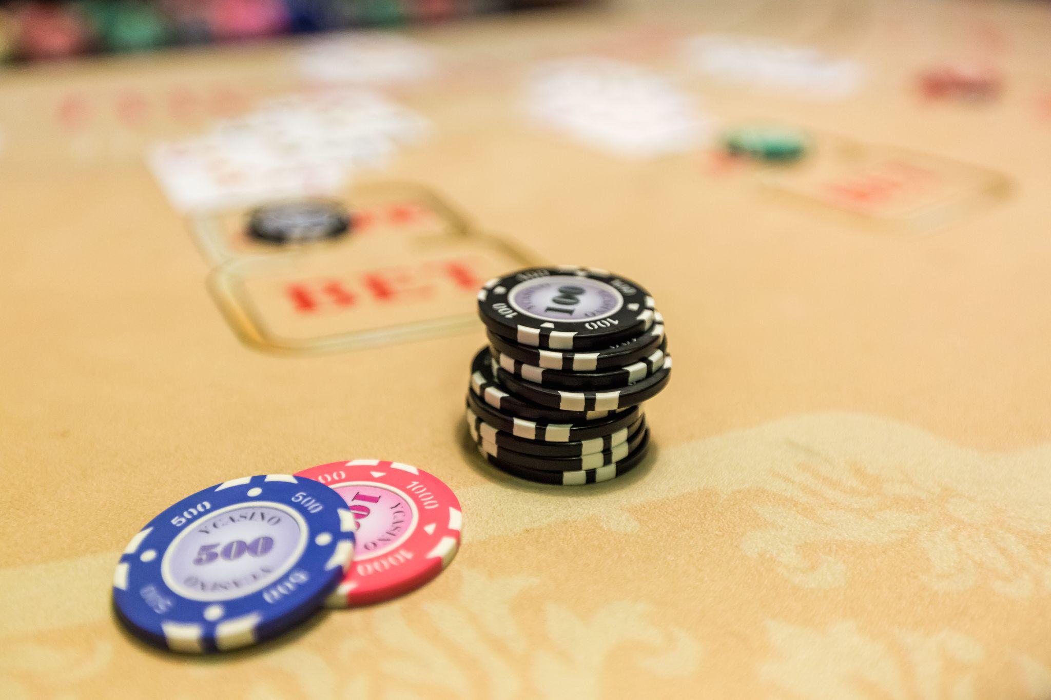 Stacks of casino chips on a gaming table with blurred playing cards in the background.