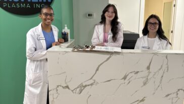 A group of people standing behind a white marble table Description automatically generated