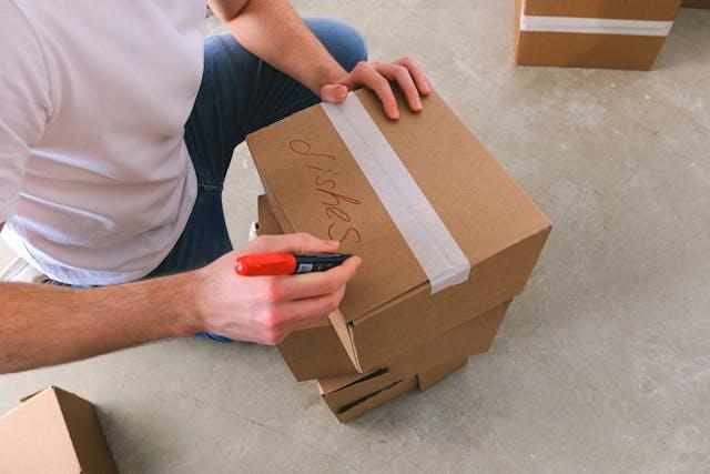 A man writing on a cardboard box.   